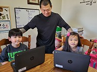 Parent working with his children in the virtual elementary program