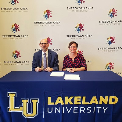 Superintendent of SASD Seth Harvatine and Lakeland University President Beth Borgen smile before signing the agreement.