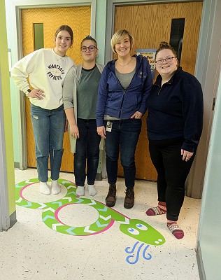 Students and Special Education Teacher Krista Everson pose on the snake feature of the new Sensory Walk.