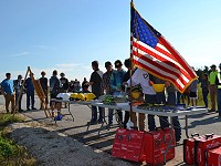 Student pick up tools and gear at house construction groundbreaking ceremony.