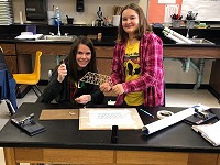 two girls display a model bridge section they've made