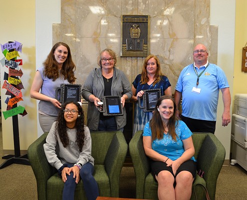 Kuck family with Urban Middle School library media specialist, teacher, principal and student displaying technology doanted by the Kuck family.