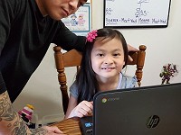 Virtual elementary school student learning at home with a parent